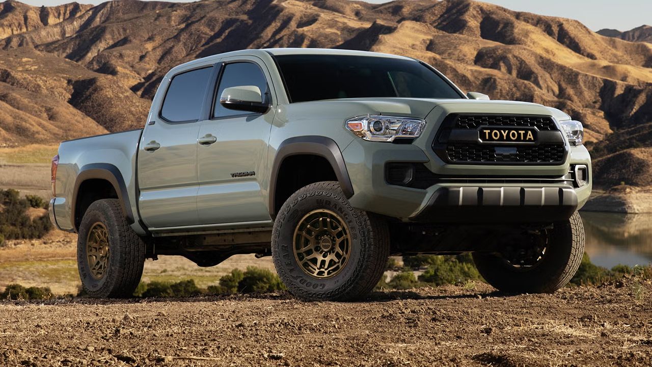 Vue 3/4 avant et latérale du Toyota Tacoma 2022 sur un chemin de terre avec vue sur les montagnes
